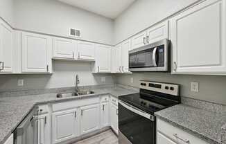 A kitchen with white cabinets and granite countertops.