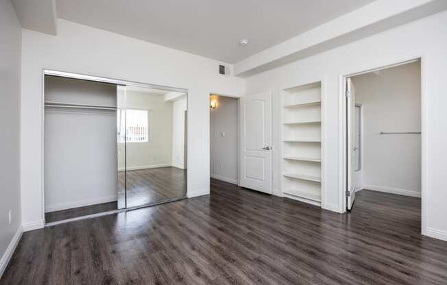 a bedroom with white walls and hardwood floors