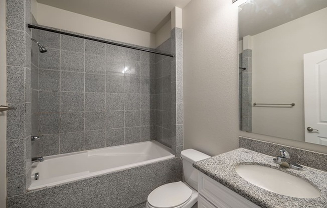 a bathroom with a tub sink and toilet and a mirror