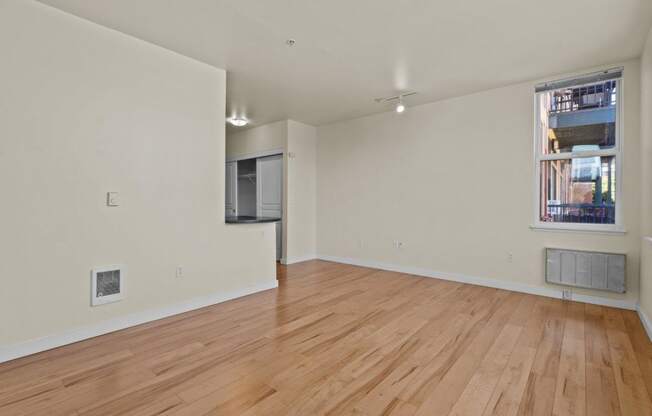 an empty living room with wood floors and a window