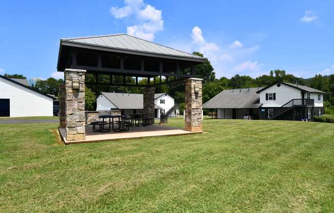 a pavilion with a table and chairs on a lawn