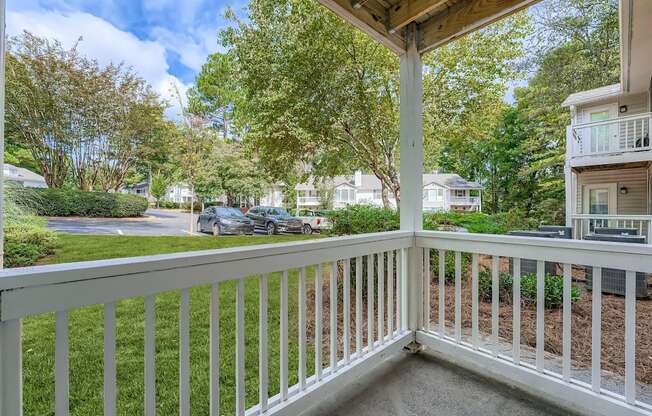 A white railing leads to a covered deck with a view of a tree-lined street.