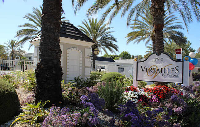 A Versailles sign is in front of a building and some trees.