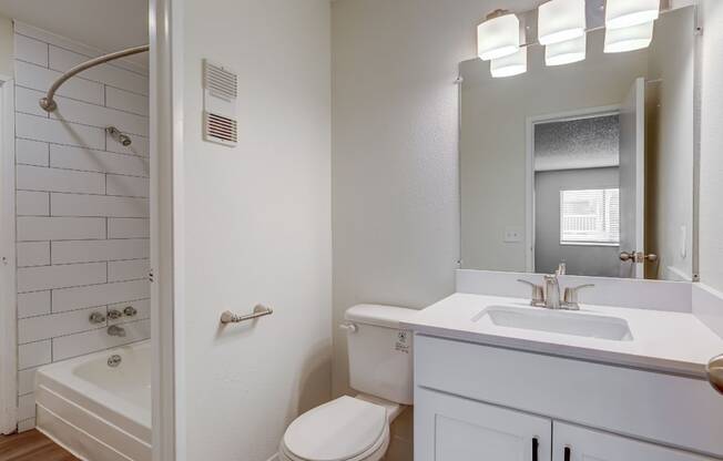 Aurora, CO Apartments – Ivy Crossing – A white bathroom with a toilet, sink, and shower.