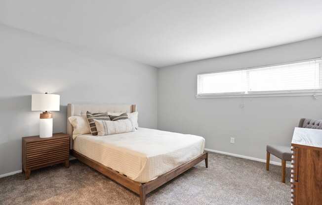 a bedroom with furnishings, a long narrow window, and plush carpeting at Mountainside Apartments