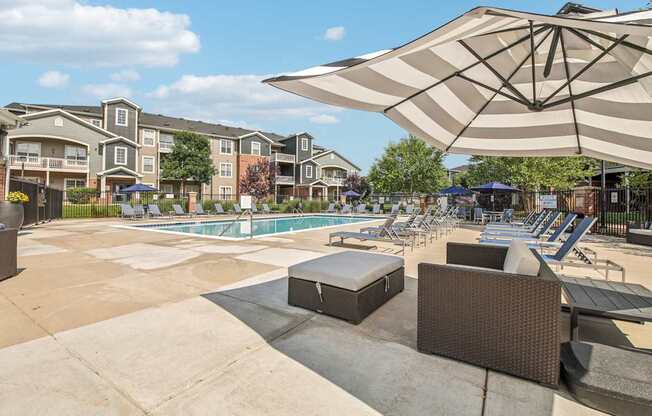 A sunny day at the poolside with a large umbrella providing shade.
