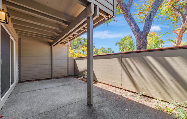 A patio area with a concrete floor and a wall with a sliding door.