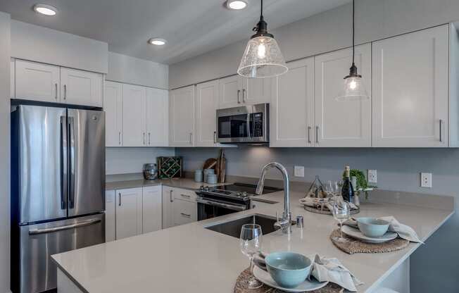 Lux Apartments Bellevue kitchen with arctic white cabinet finishes, undermount sink and quartz countertops and stainless-steel appliances, including overhead microwave, double-door refrigerator, and f