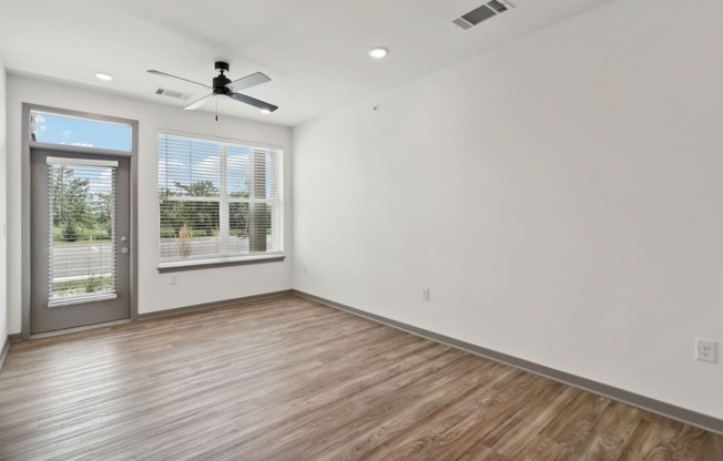 a living room with white walls and a window and a ceiling fan at The Depot in The Depot Raymore, MO 64083