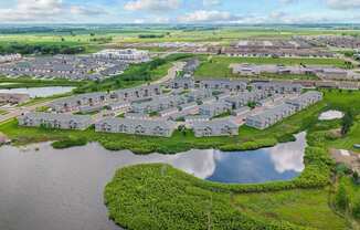 A bird's eye view of a residential area with houses surrounded by water and greenery.