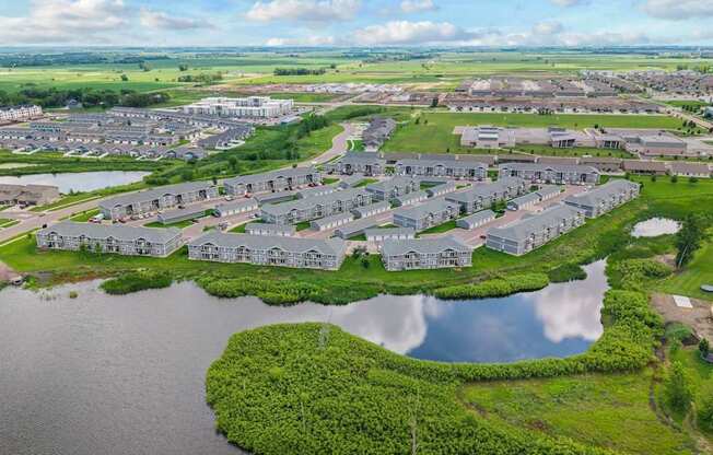 A bird's eye view of a residential area with houses surrounded by water and greenery.