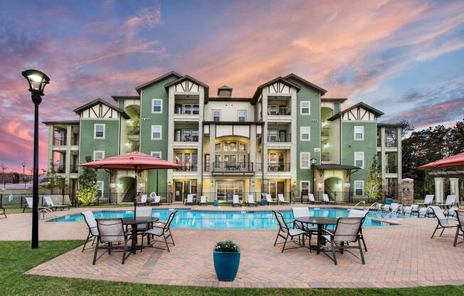 a swimming pool with patio furniture and a building in the background