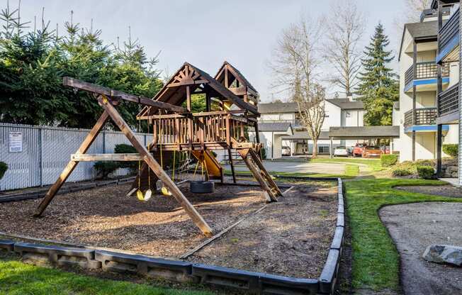 a swing set in a park with a building in the background
