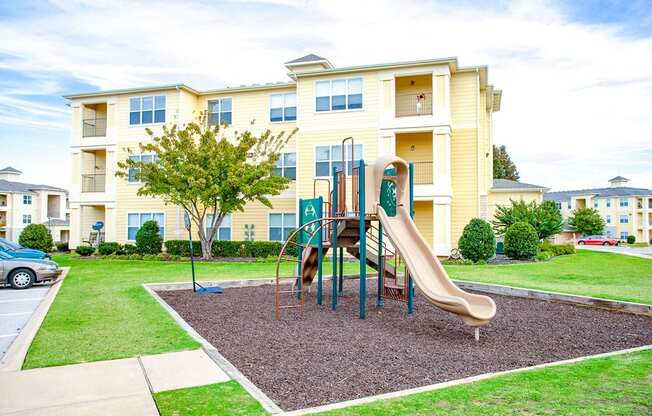 a playground with a slide in front of an apartment building