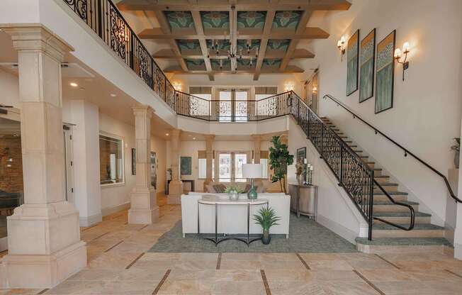 A large foyer with a staircase and a table with a plant on it.