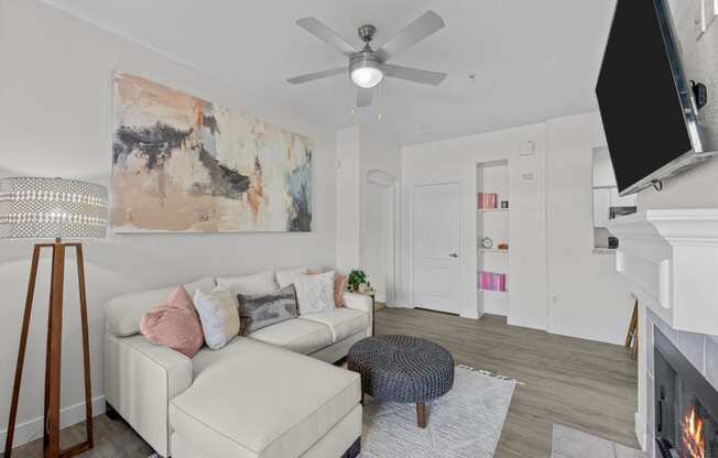 a living room with a white couch and a ceiling fan