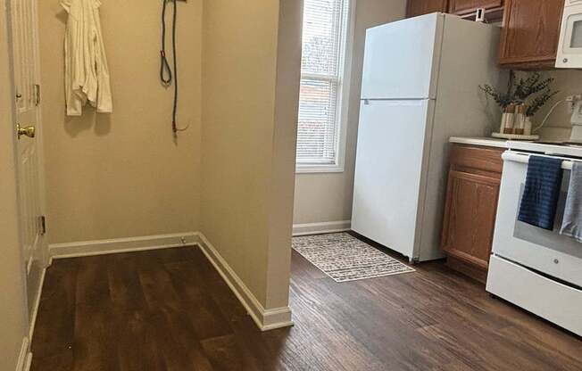 A white refrigerator is in a kitchen with wood floors.