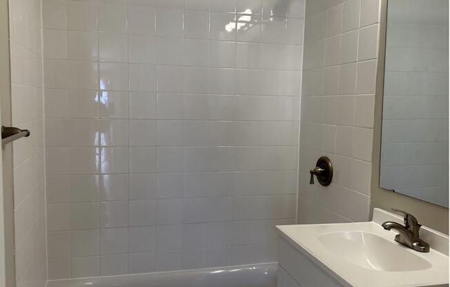 A white bathroom with a white tub and sink.