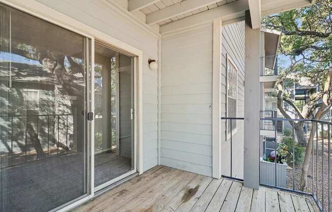 A white house with a sliding glass door and a wooden deck.