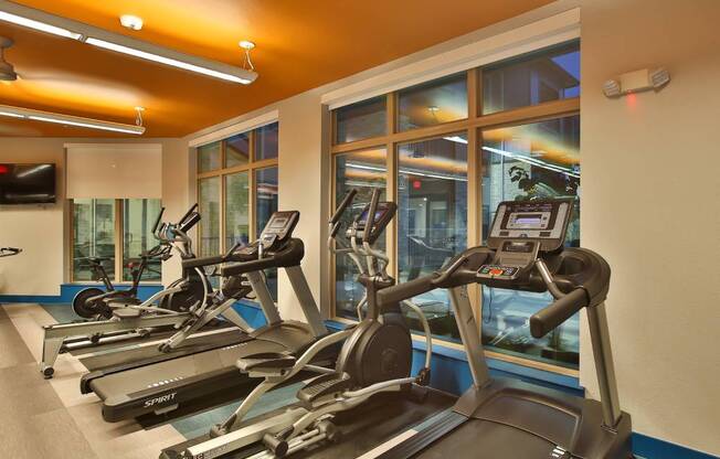 a gym with cardio machines and a window
