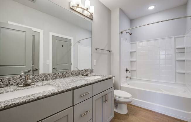 bathroom with dual vanity, granite-style countertops, and hardwood-style flooring