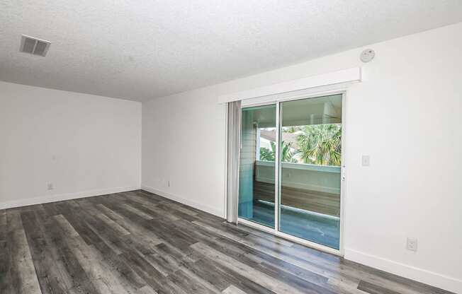 an empty living room with a sliding glass door to a patio