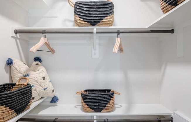 A white closet with clothes hanging on hangers.
