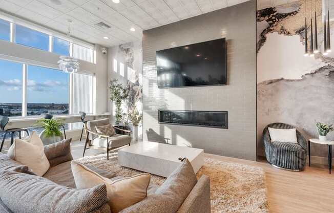 A modern living room with a large couch, a fireplace, and a flat-screen TV mounted on the wall.