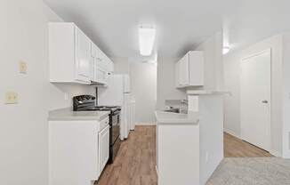 A white kitchen with wood floors and white cabinets.