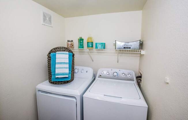 A laundry room with a washer and dryer and a basket on top of the washer.