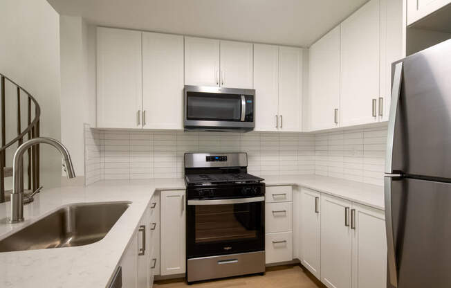A kitchen with white cabinets and stainless steel appliances.