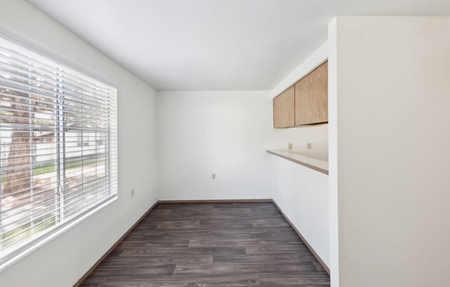 an empty living room with a large window and wood flooring