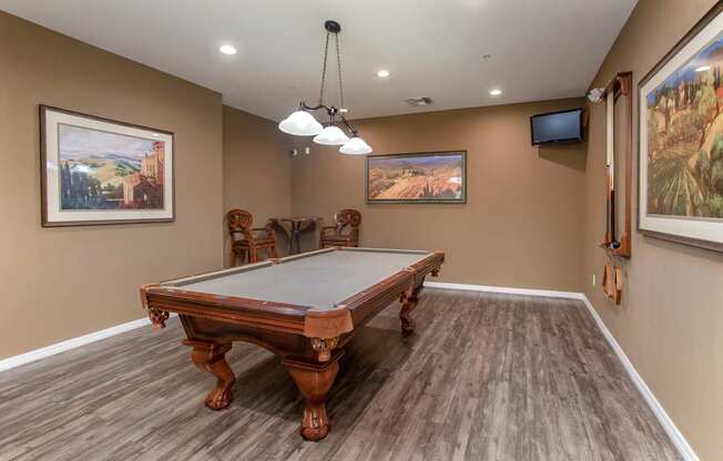 A pool table in a room with brown walls and wooden flooring.