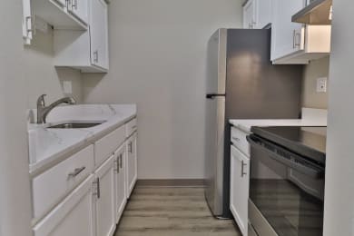 an empty kitchen with white cabinets and stainless steel appliances