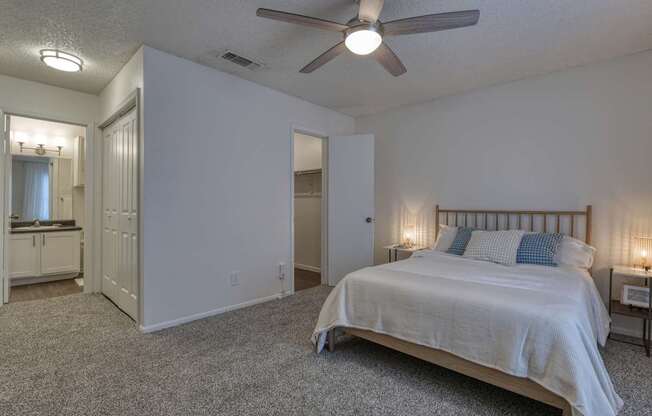 A bedroom with a bed, a dresser, and a ceiling fan.