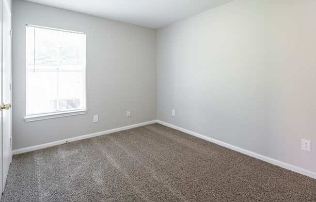 an empty room with carpet and a window