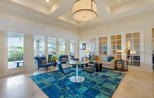 A spacious living room with a blue rug and a large window.