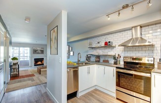 Seattle Luxury Apartments - Union Bay - Kitchen with White Tile Backsplash, Stainless-Steel Appliances, and Floating Shelves
