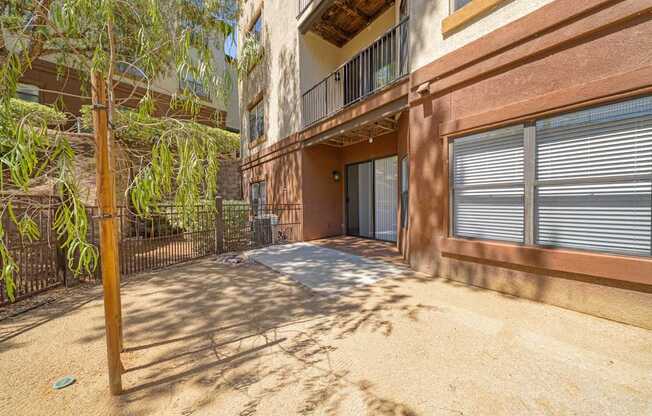 A sandy courtyard with a building and a tree in the background.