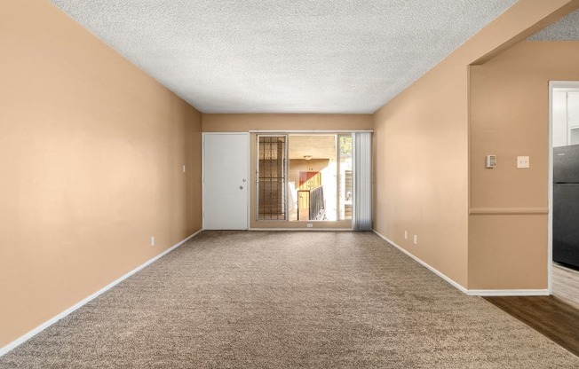 a living room with a carpeted floor and a door to a hallway