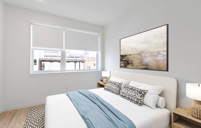 Minimalist bedroom with a comfortable bed, large abstract artwork above, and a neutral color palette creating a serene atmosphere.