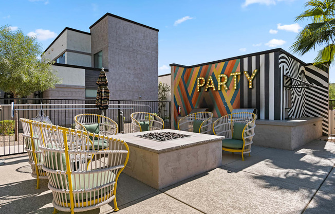 a patio with chairs and a fire pit in front of a building