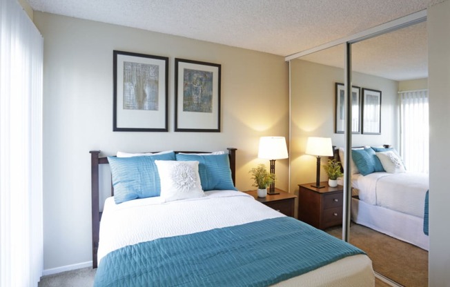 Bedroom with mirrored closet doors, full size bed and night stand  at Pacific Sands, San Diego, California