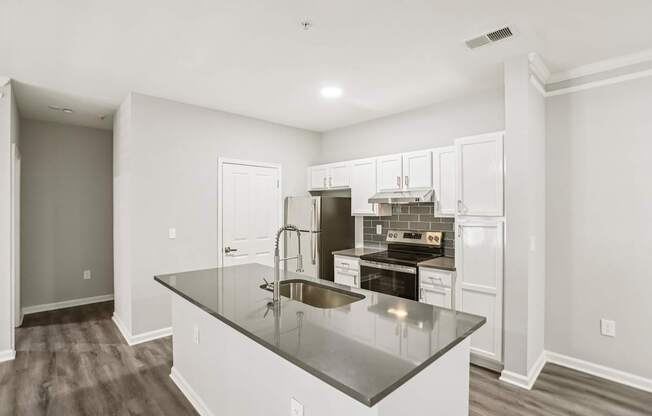 A kitchen with a black granite countertop and white cabinets.