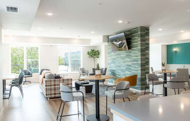 A modern living room with a large window, a couch, a coffee table, and a TV mounted on the wall.