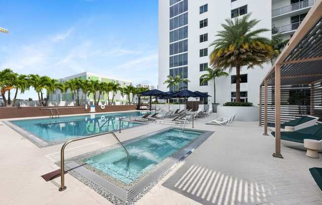 a swimming pool with chaise lounge chairs and palm trees in front of a tall building