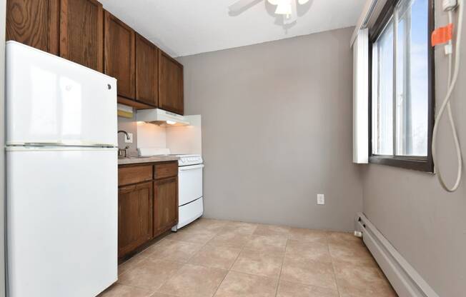 an empty kitchen with a refrigerator and a window. Roseville, MN Rosedale Estates