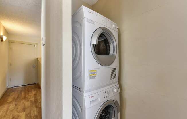 White stacked washer and dryer inside apartment home.