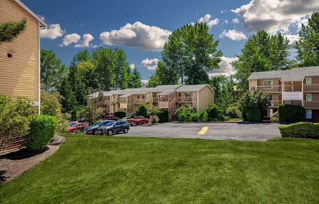 A sunny day at the apartment complex with cars parked in the parking lot.