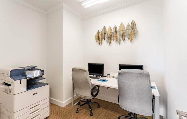 a home office with two chairs and a desk with a computer and a printer